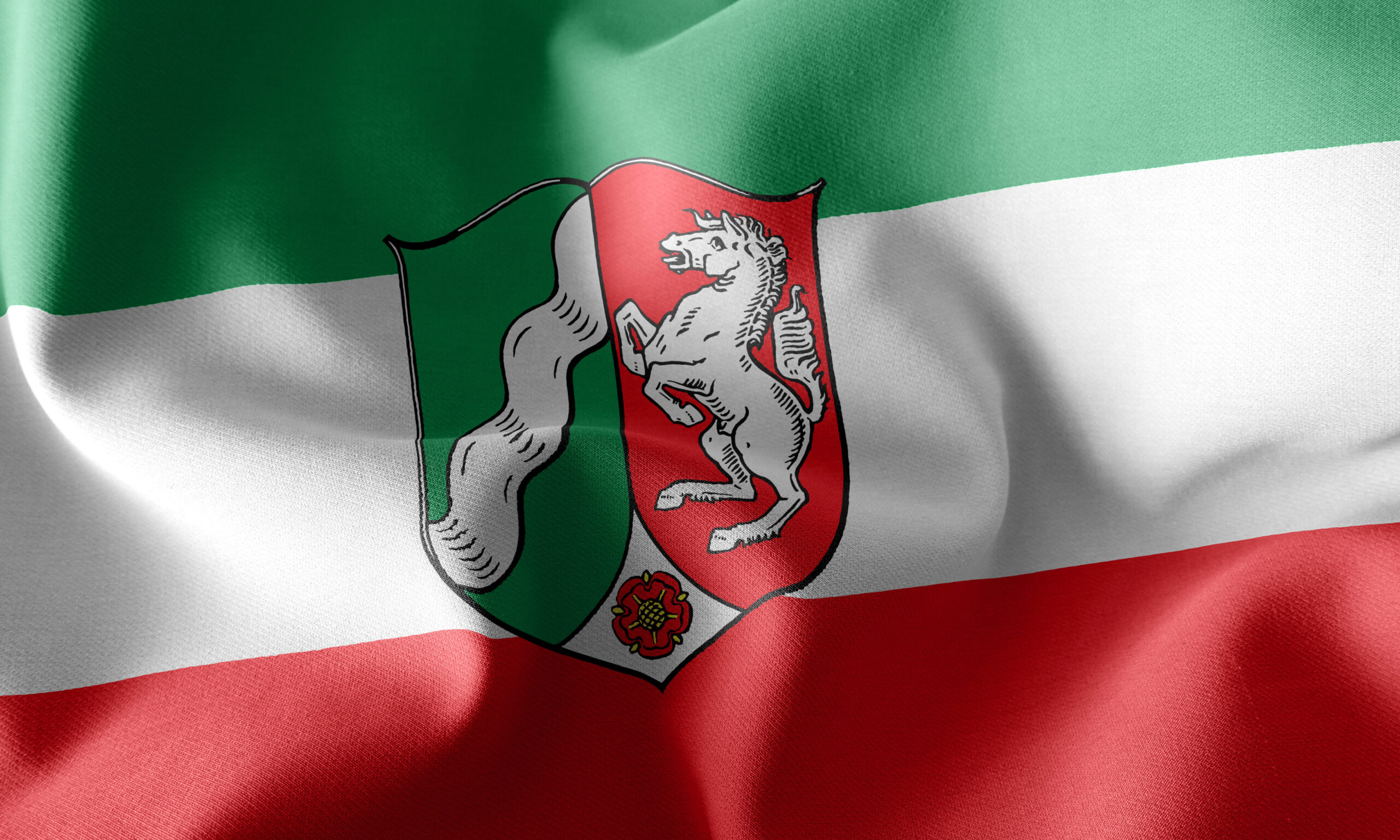 „Flagge von Nordrhein‑Westfalen mit grün‑weiß‑roten Querstreifen und dem Landeswappen in der Mitte.“