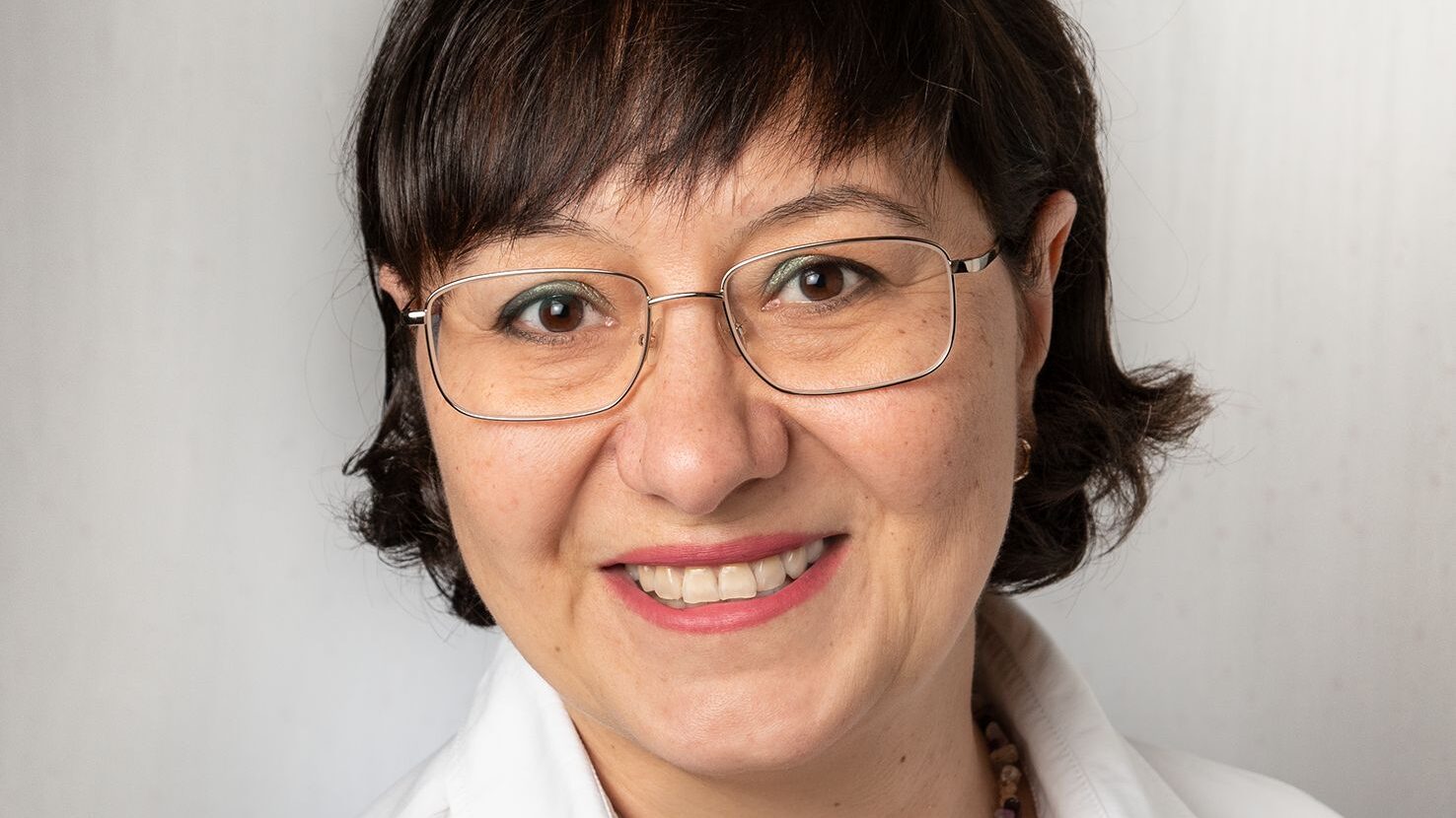 Das Bild zeigt die neue Kollegin, Halyna Waldeyer. Sie hat schwarze, kinnlange Haare, trägt eine Brille und lächelt freundlich in die Kamera.